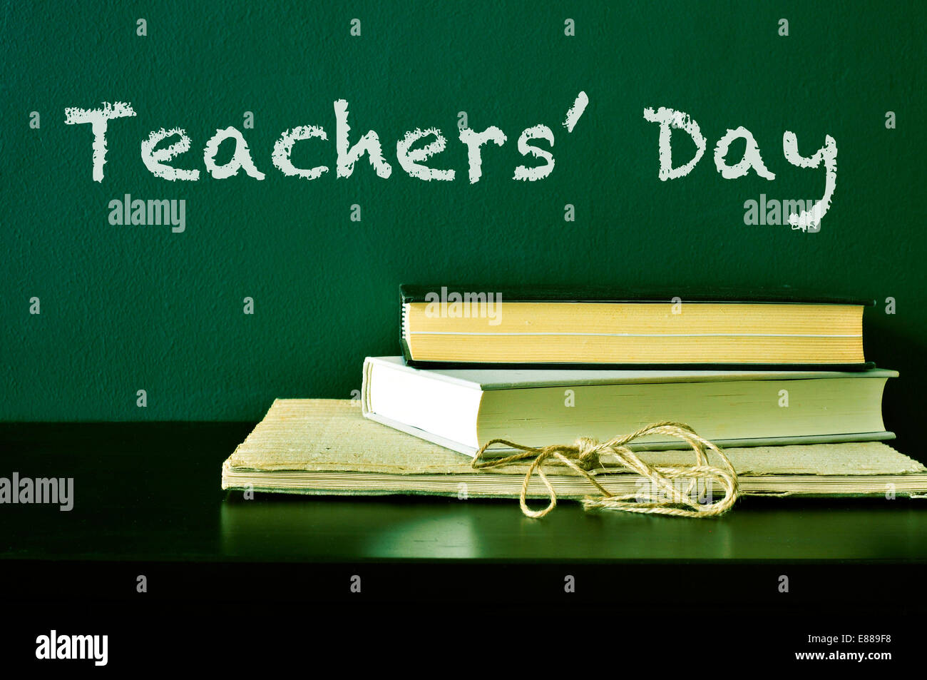 der Text Teachers Day mit Kreide auf einer grünen Tafel und einige Bücher auf dem Schreibtisch geschrieben Stockfoto