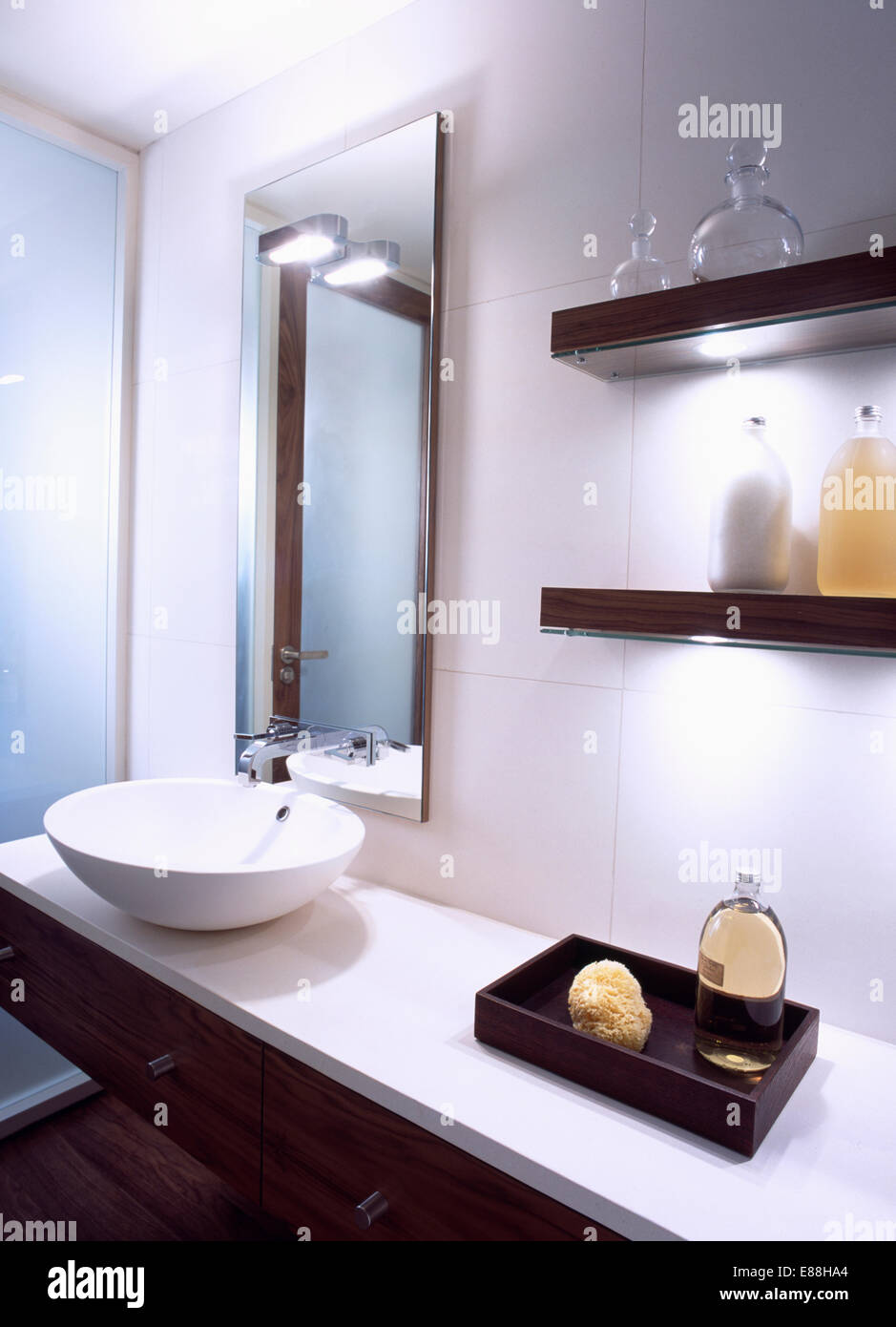 Spiegel über Schüssel Becken auf Waschtischunterbau mit Schwamm und Bad Öl in hölzerne Aufbewahrungsbox unten einfache Wand-Regale Stockfoto