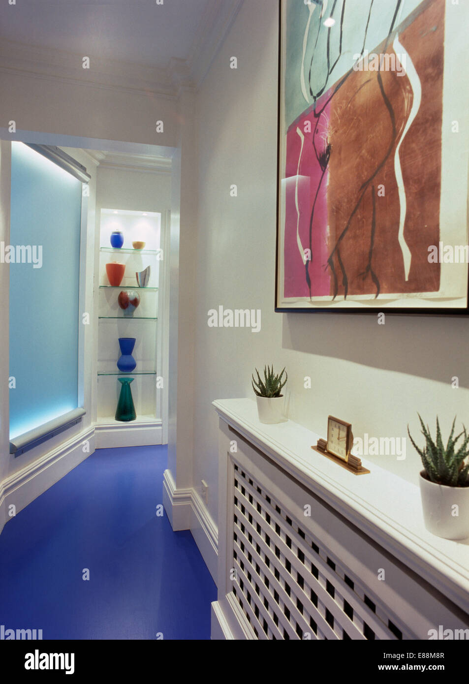 Bild über Heizkörper Abdeckung in schmale weiße Halle mit leuchtend blauen Bodenbelag und Beleuchtung über shgelves Stockfoto