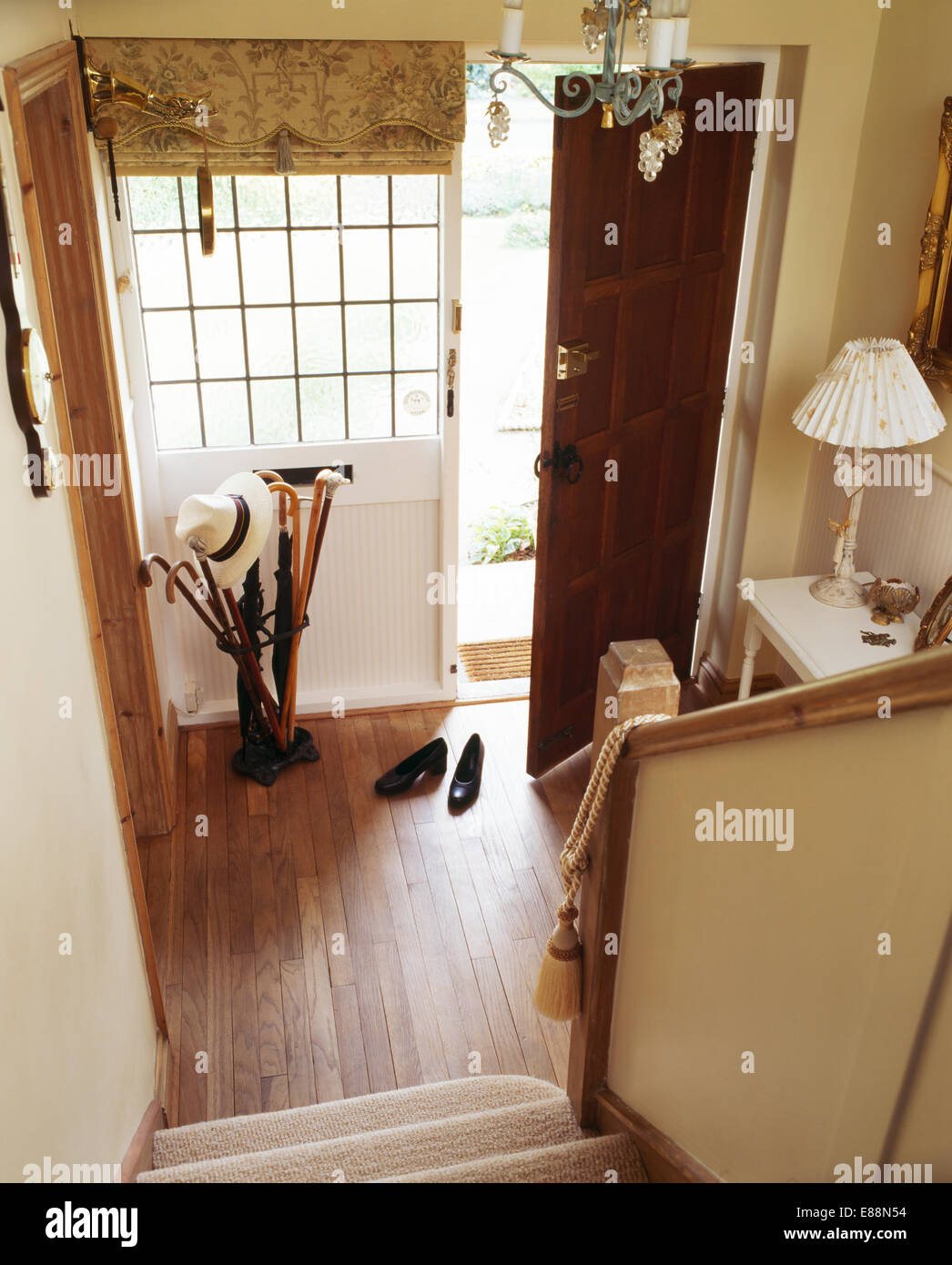 Blick hinunter Treppe am Holzboden in kleinen Creme Halle mit gemusterten Blind auf hohes Fenster neben der Eingangstür Stockfoto