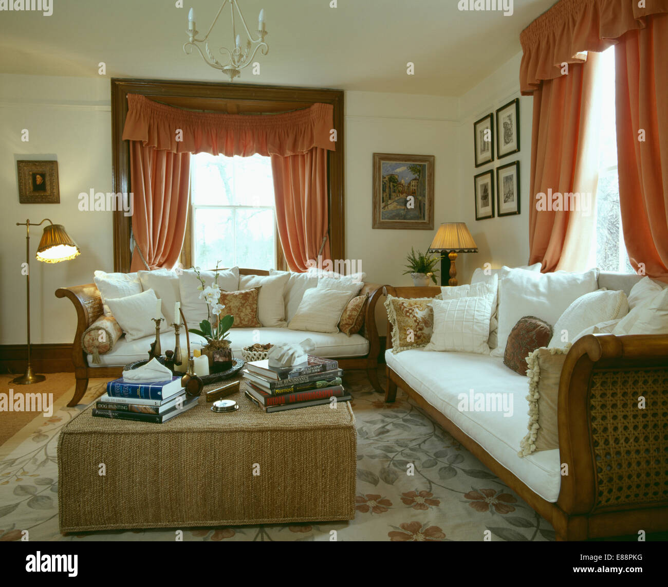 Weißen Kissen auf französischem Sofas im Wohnzimmer mit maßgeschneiderten Hocker und Pfirsich Vorhänge Stockfoto