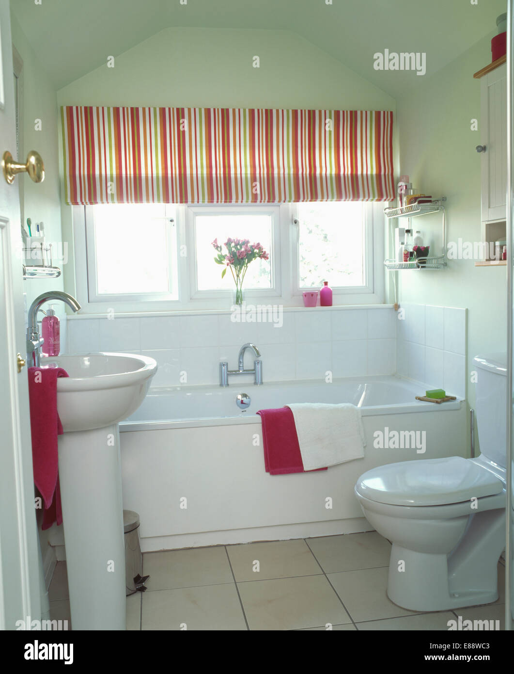 Rot gestreifte Blind über Bad im modernen weißen Badezimmer mit weißen Sockel Becken und rosa Handtücher Stockfoto