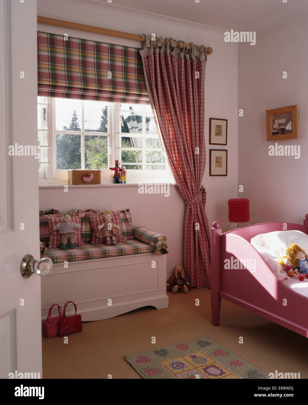 Multi-geprüfte Blind und Vorhänge am Fenster über weiße Brust mit geprüften Kissen im Kinderzimmer Stockfoto