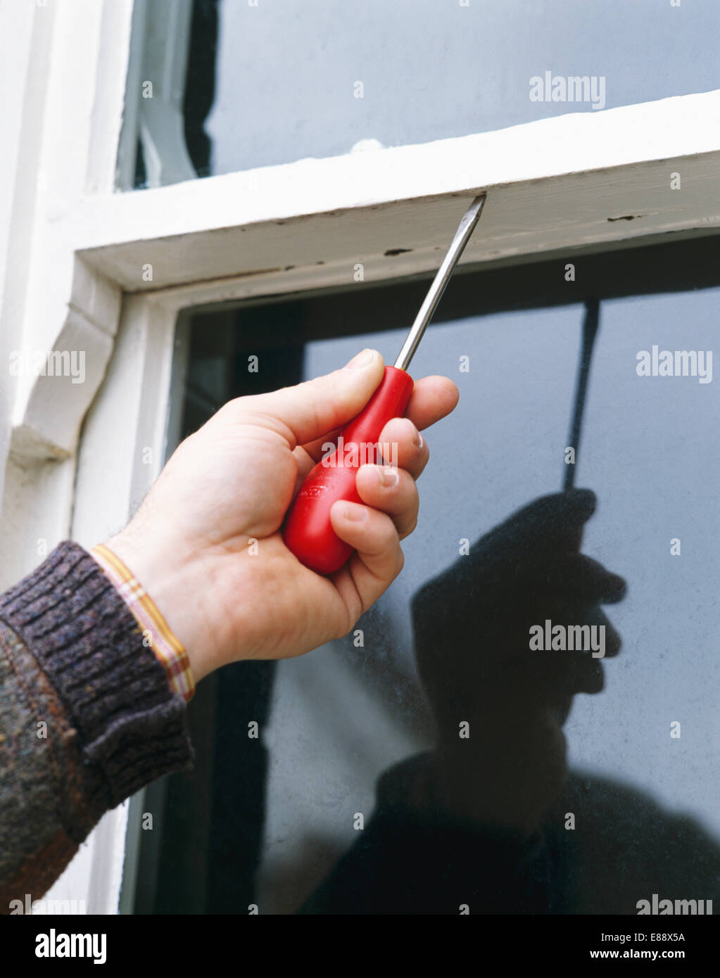Nahaufnahme von Hand mit Schraubendreher gegen Schiebefenster Stockfoto