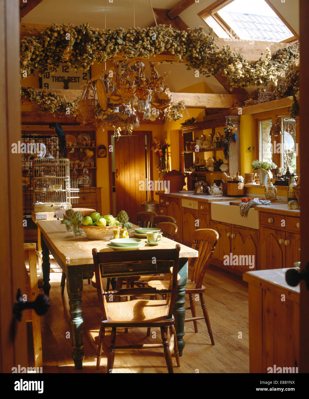 Alte Kiefern Tisch und Stühle im Bauernküche mit Hop Bine Kranz auf Holzbalken Stockfoto