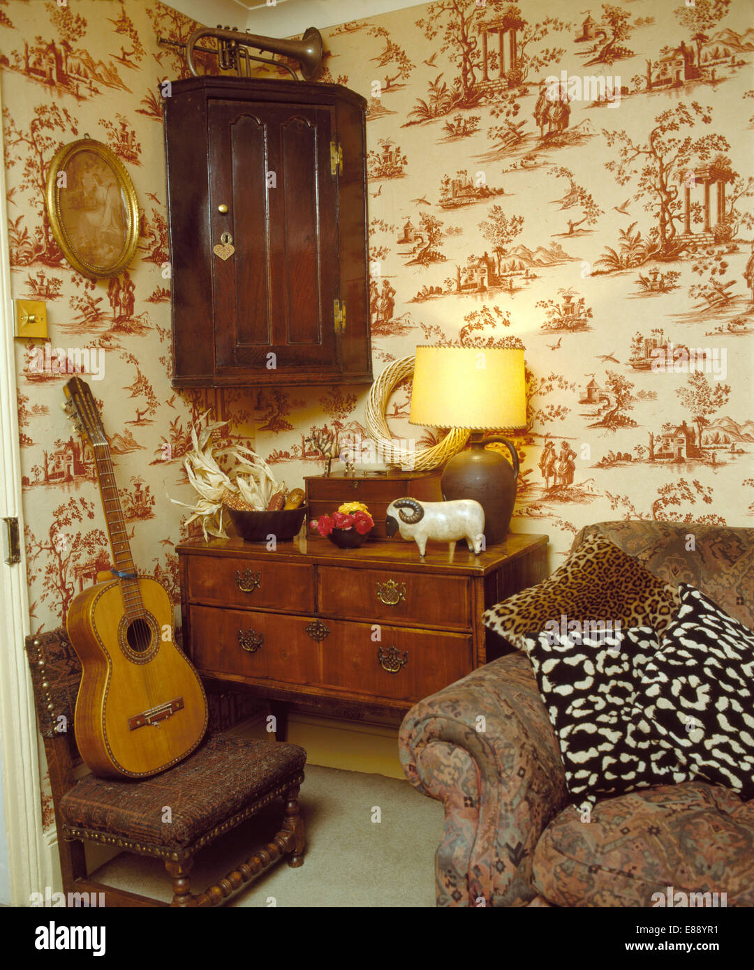 Antiker Eckschrank oben kleine Kommode im Ferienhaus Wohnzimmer mit  Toile-de-Jouy-Tapete Stockfotografie - Alamy