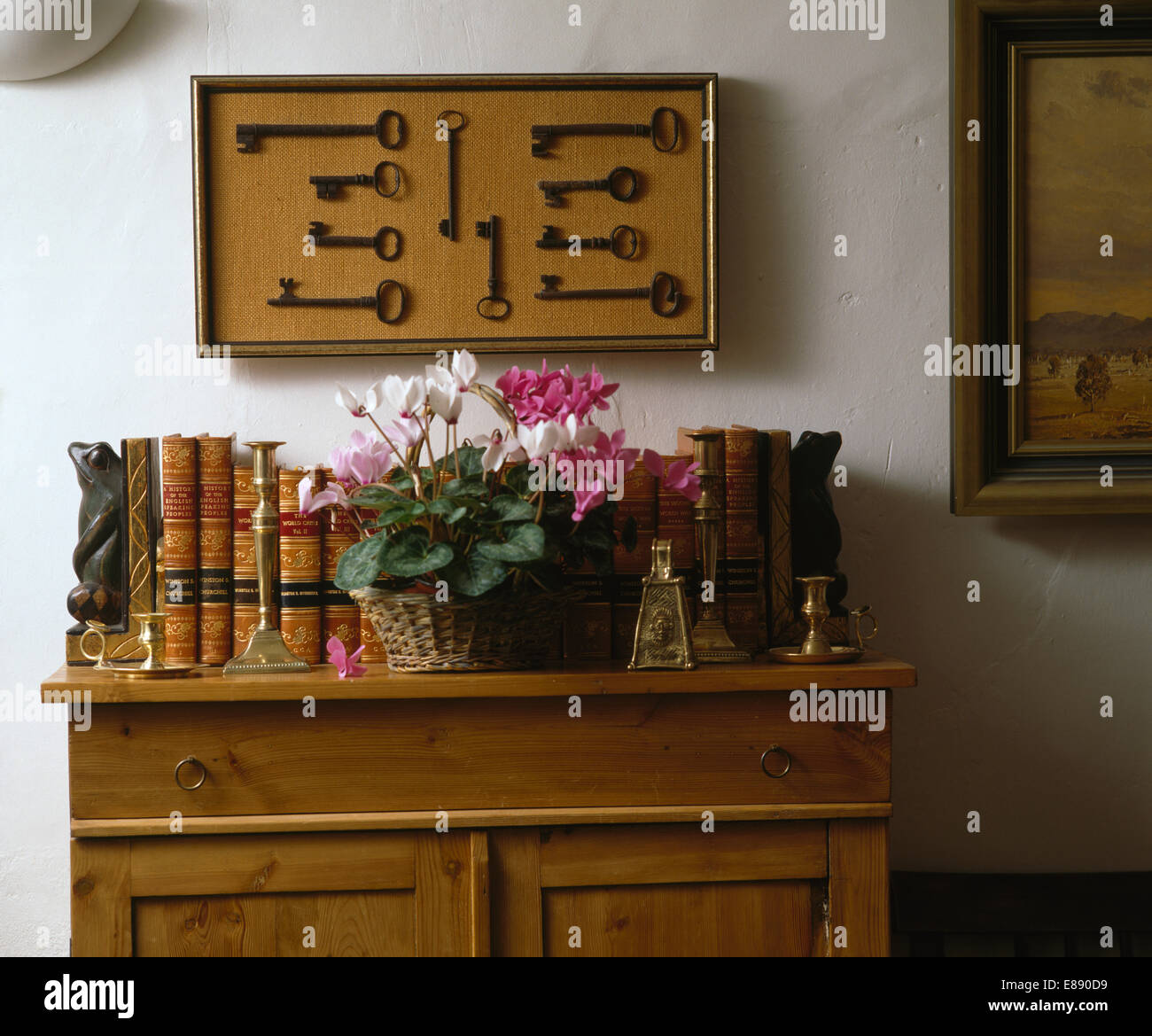 Gerahmten Sammlung von alten Schlüssel an Wand über alte Kiefer Schrank mit Topf Alpenveilchen und Oldtimer Bücher Stockfoto