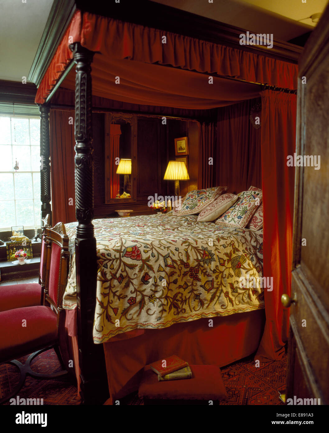 Antike Schlafzimmereinrichtungen Bett mit roten Vorhängen und Crewelwork Bettdecke im traditionellen Landhausstil Schlafzimmer Stockfoto
