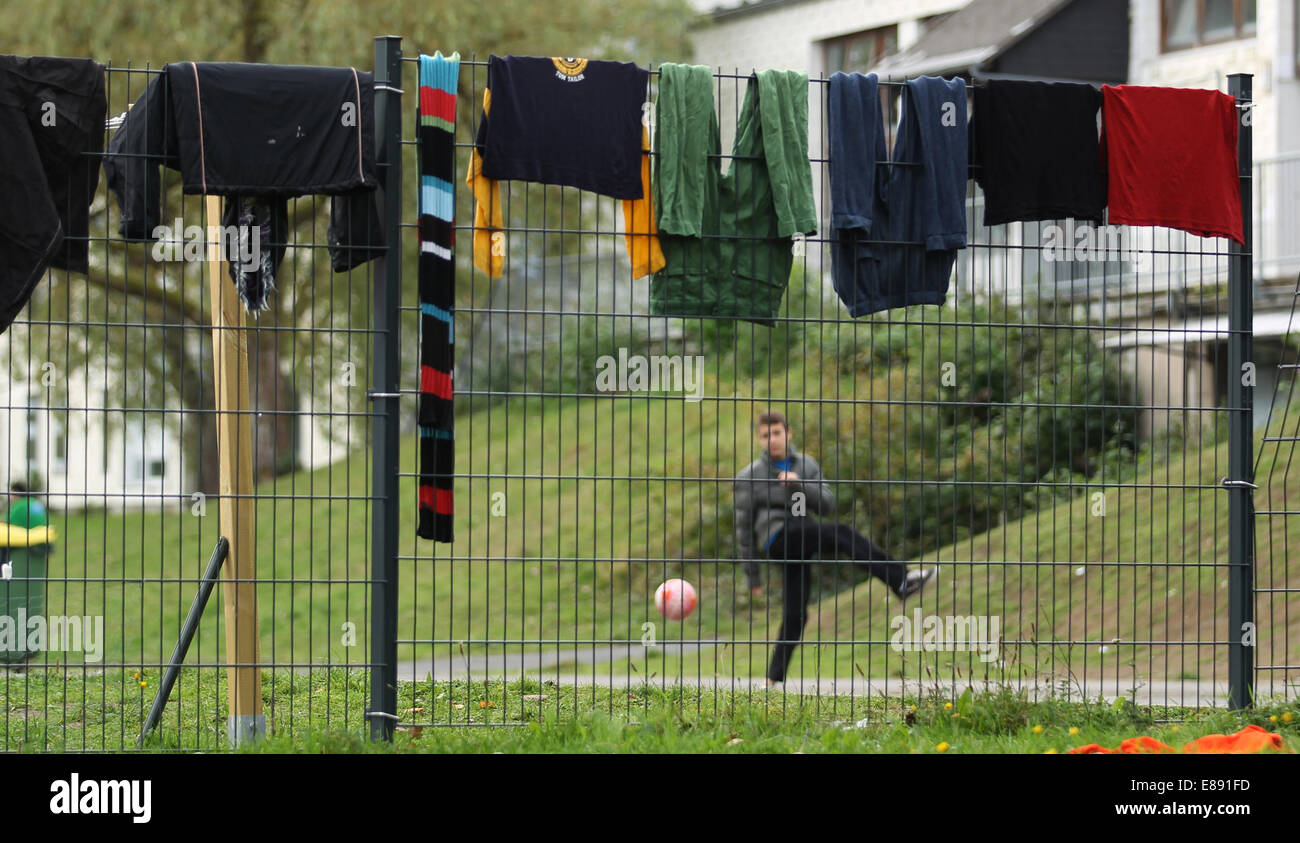 Wäsche hängt zum Trocknen auf einen Zaun, während ein junger Mann in Burbach, Deutschland, 29. September 2014 Fußball spielt. Zuhause ein Flüchtling in Burbach wurden private Sicherheitspersonal beschuldigt Asylbewerber zu missbrauchen. Die ehemaligen Siegerland-Kaserne werden als Notunterkünfte für Asylbewerber und Flüchtlinge eingesetzt. Foto: Ina Fassbender/dpa Stockfoto