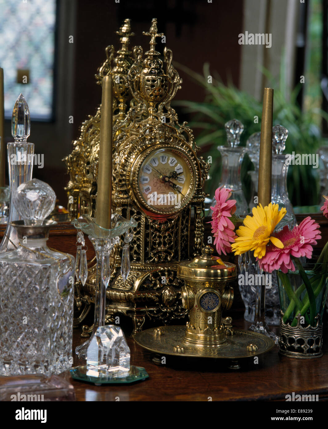 Nahaufnahme der Antike Uhr und geschliffenem Glas Karaffe mit kleine Vase mit Gerbera Stockfoto