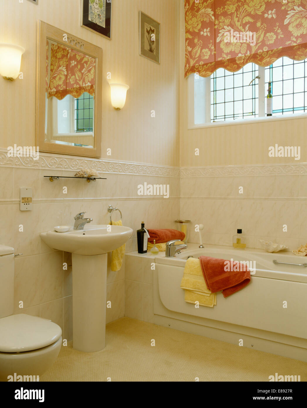 Floral Blind am Fenster über der Badewanne in der Mitte gefliest Bad mit Wandleuchten auf beiden Seiten des Spiegels über Sockel Becken Stockfoto