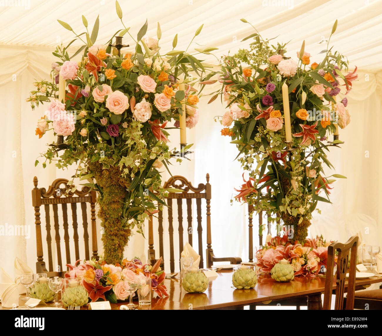 Rosa Rosen in üppige Blumenarrangements auf Tisch im Festzelt geschmückt für eine Hochzeit Stockfoto