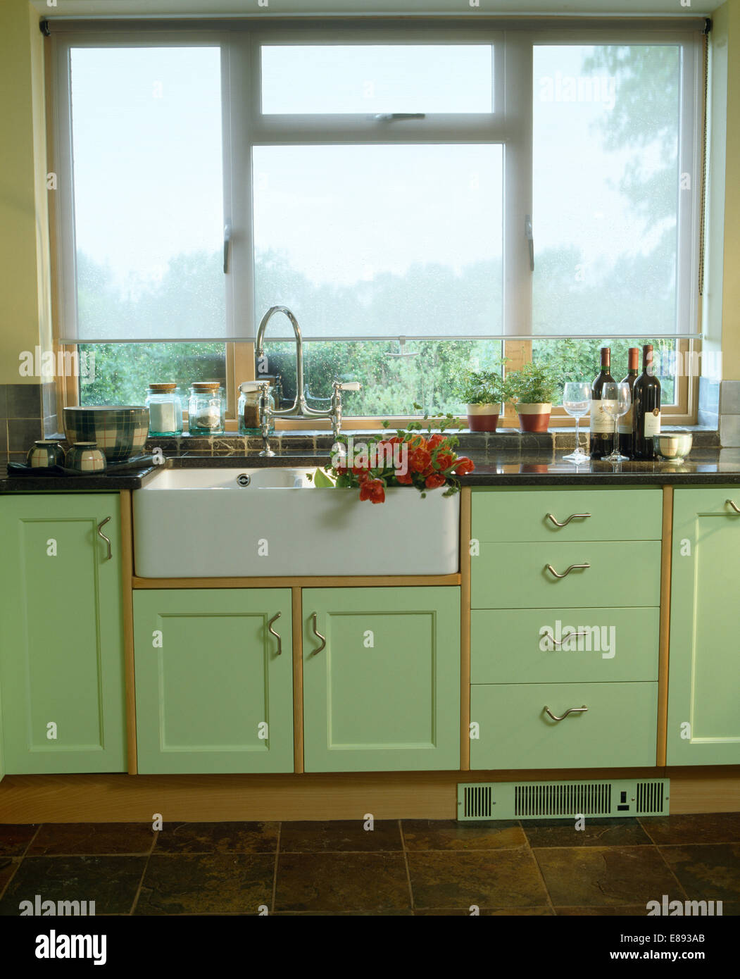 Weiß blind auf Fenster über Belfast einsinken Landhausküche mit grünen montierten Einheiten Stockfoto