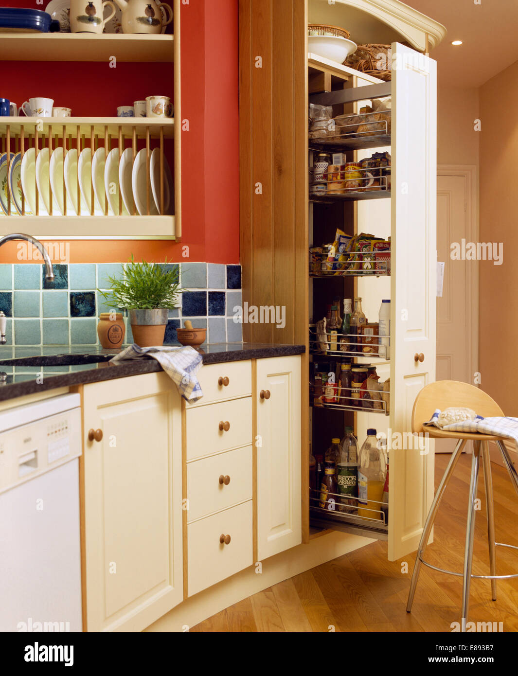 Herausziehen der Schubladen im Vorratsschrank Schrank in der Küche mit blau  gekachelten Spritzschutz unter Tellerhalter Stockfotografie - Alamy