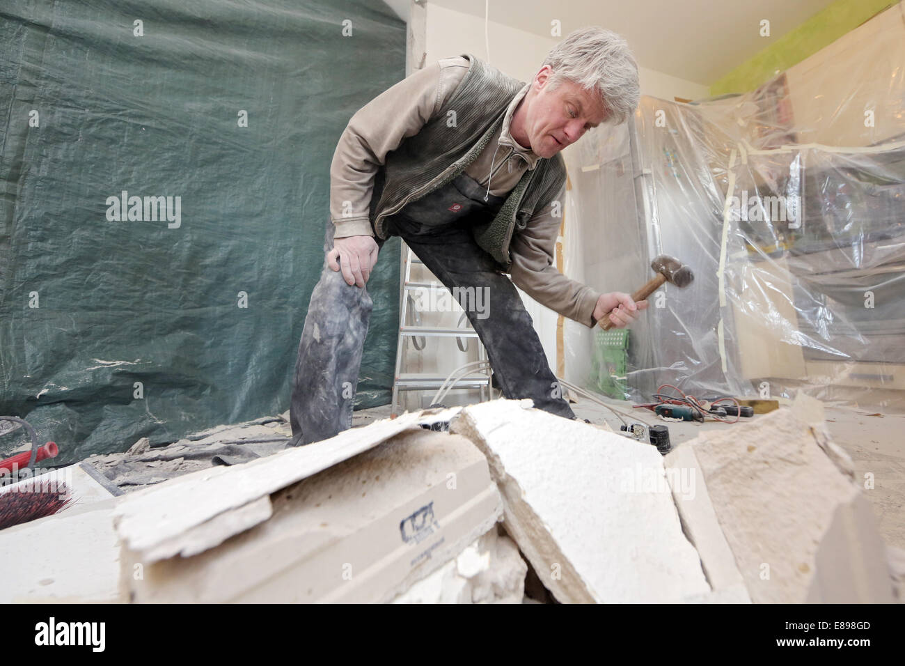 Berlin, Deutschland, Handwerker zerschlägt Ziegel mit einem hammer Stockfoto