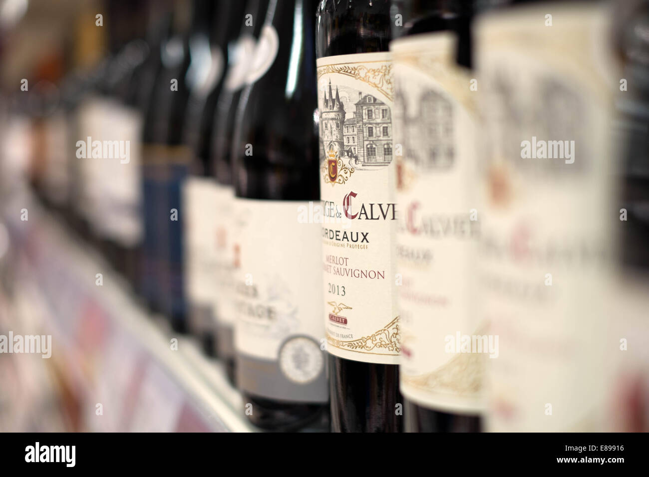 Eine Auswahl an roten Wein in Flaschen auf einem Regal in einem Zweig der Sainsbury Supermarkt Preise & Angebote anzeigen Stockfoto