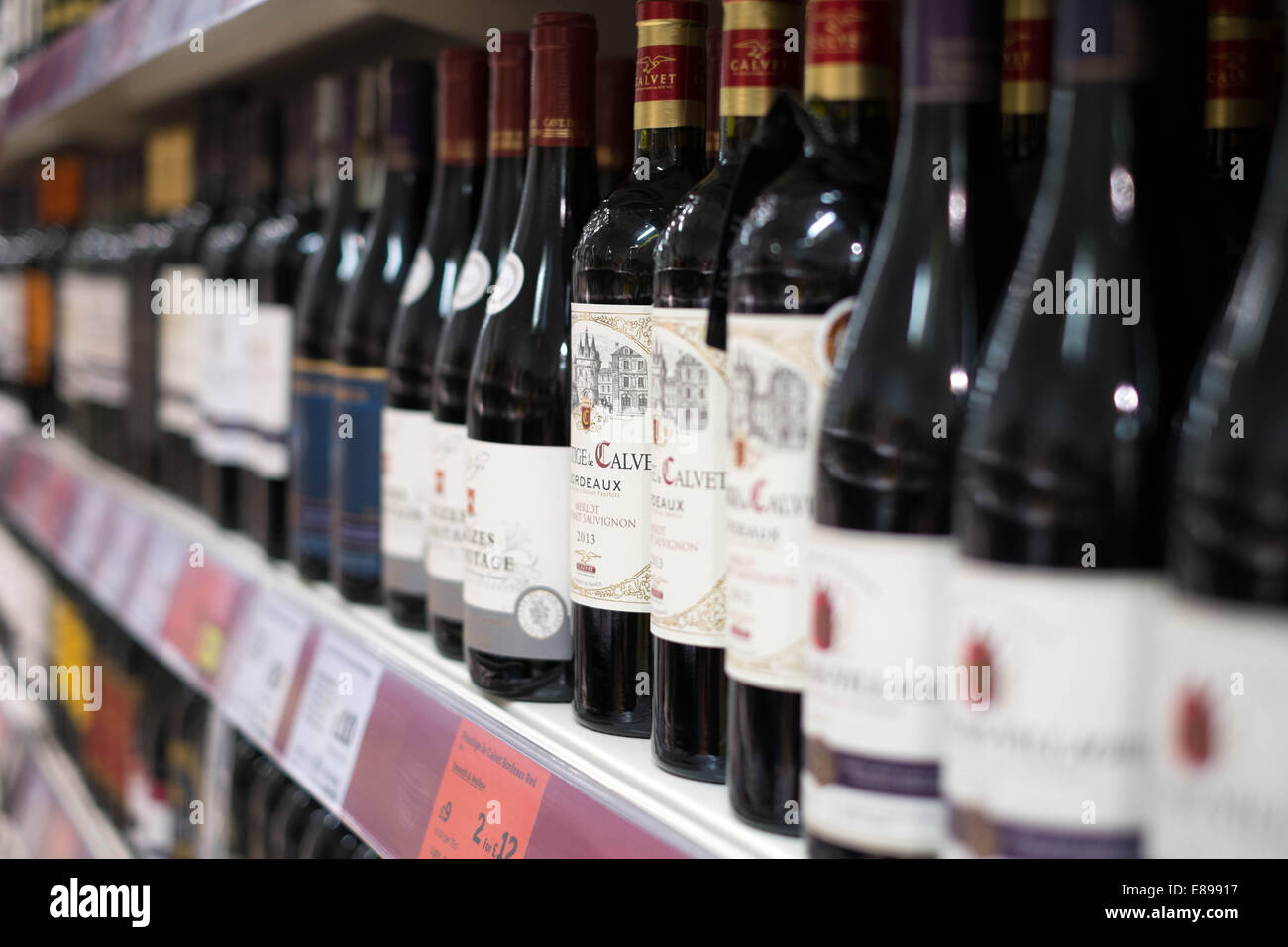 Eine Auswahl an roten Wein in Flaschen auf einem Regal in einem Zweig der Sainsbury Supermarkt Preise & Angebote anzeigen Stockfoto