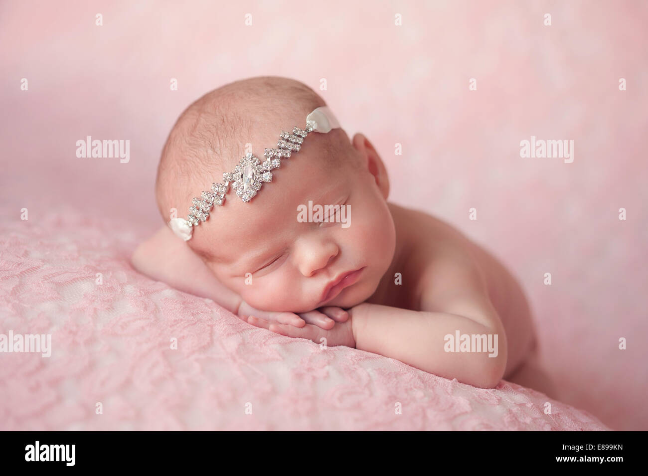 Portrait von 10 Tage alten Baby Mädchen. Sie trägt ein Strass Stirnband und schläft auf Licht rosa Spitze Material. Stockfoto