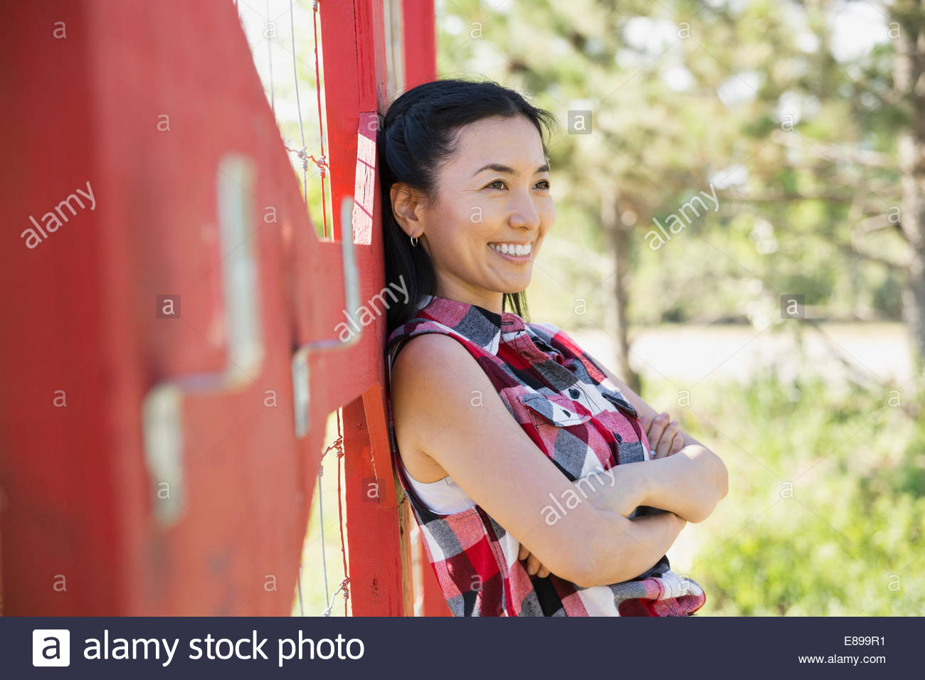 Lächelnde Frau stützte sich auf Zaun im Garten Stockfoto