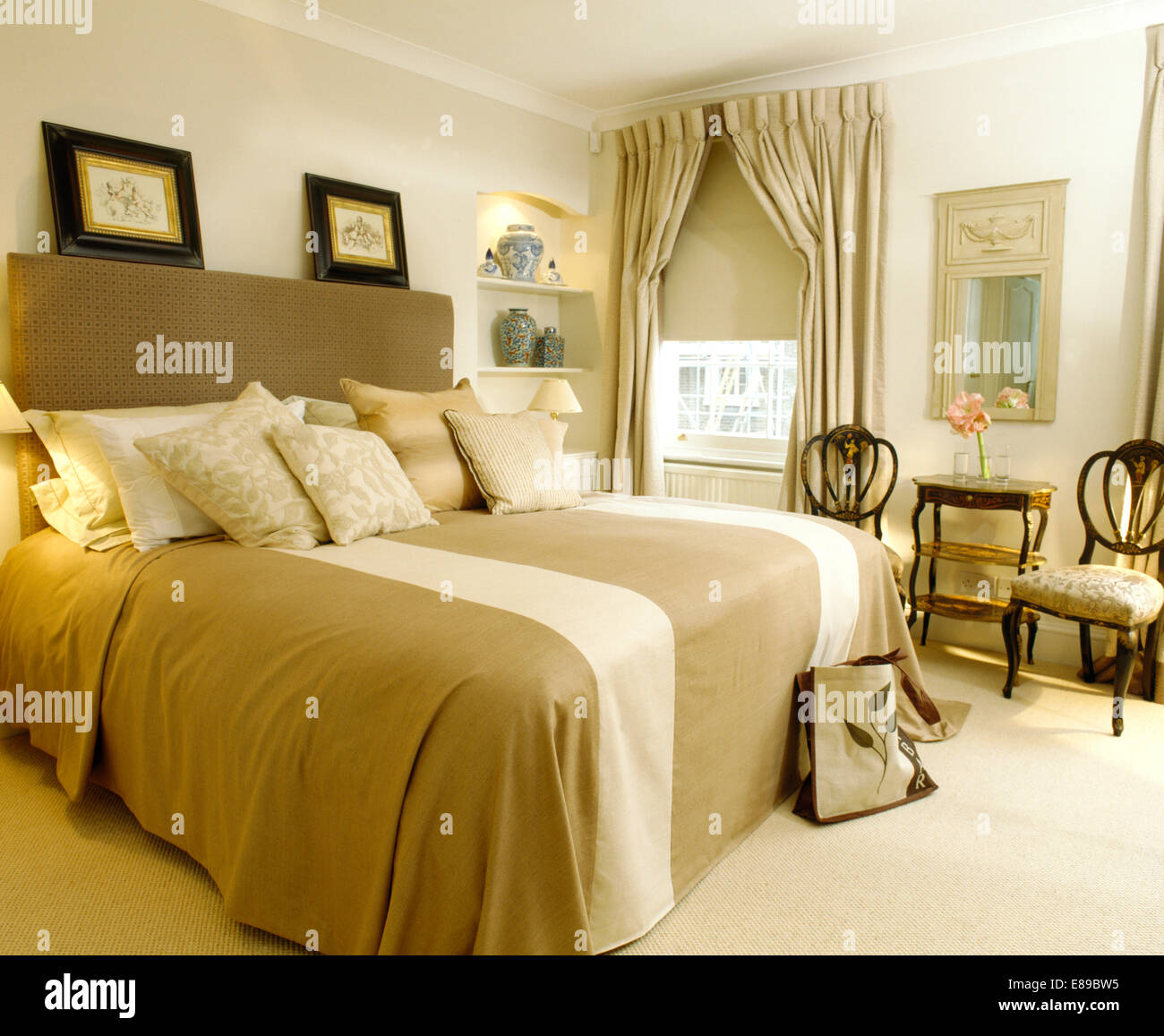 Creme und Beige gestreiften Bettdecke auf Doppelbett mit gepolstertem Kopfteil in Schlafzimmer mit Sahne Teppich Stockfoto
