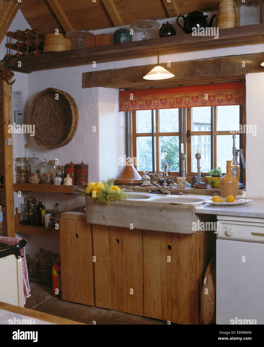Rot blinde Fenster über dem alten Steingut einsinken Cottage-Küche mit rustikalen Holz und Holz Regale Stockfoto