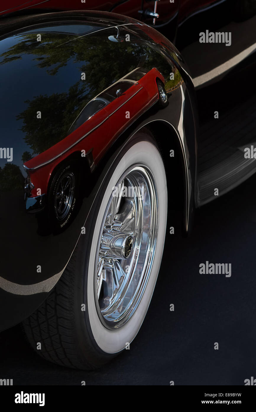 Klassische rote Oldtimer auf der Vorderseite eines Schwarzen antiken Ford Delixe Auto wider. Stockfoto