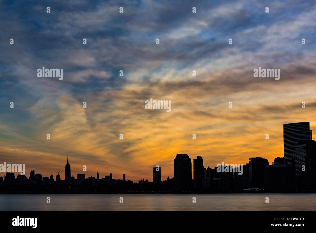 Die Skyline von New York silhouette weckt zu einem wunderschönen Sonnenaufgang mit einem spektakulären Himmel als Hintergrund. Stockfoto