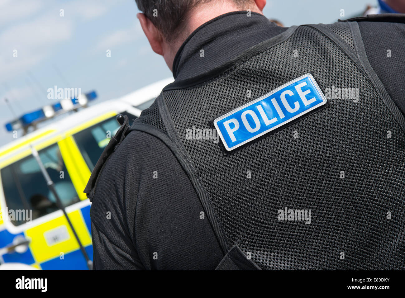 Kaukasischer britische männlicher Polizist in modernen Polizeiuniform mit dem Wort Polizei genäht auf der Rückseite der seine taktische Weste Stockfoto