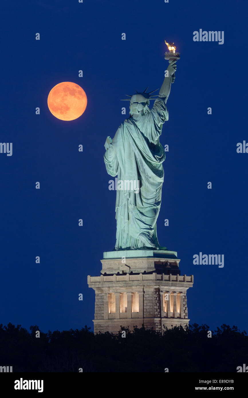 Der super Mondaufgang neben der Statue of Liberty während der blauen Stunde. Stockfoto