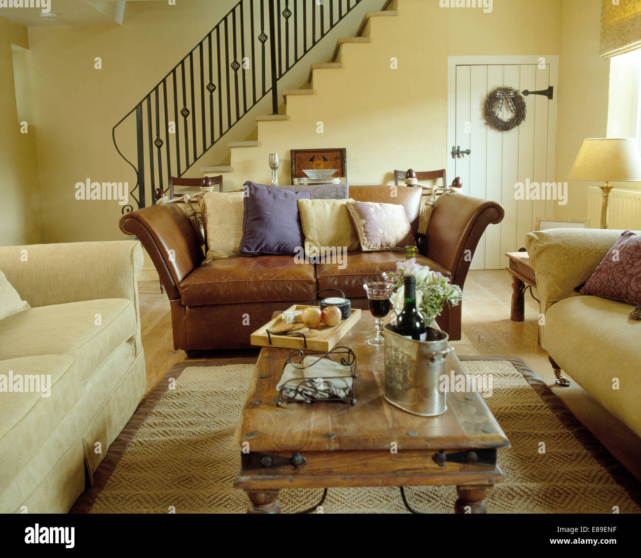 Cremefarbene Sofas mit Braune Ledercouch, um indonesische Couchtisch im  modernen Wohnzimmer angeordnet Stockfotografie - Alamy