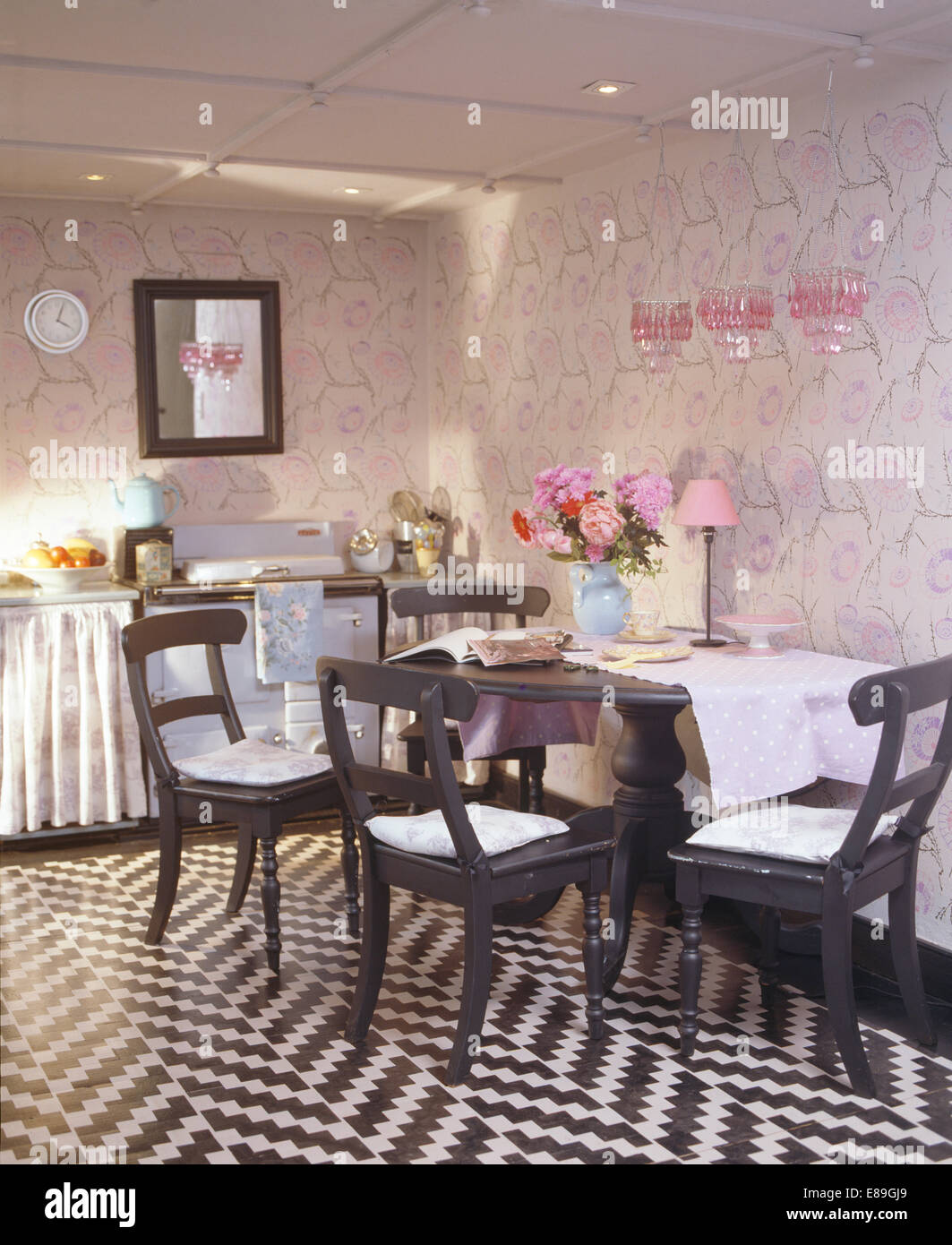 Schwarz + weiß Zick Zack perforierten Boden in Küche Esszimmer mit gemalten schwarzen Stühlen und Tisch mit perforierten Wänden Stockfoto