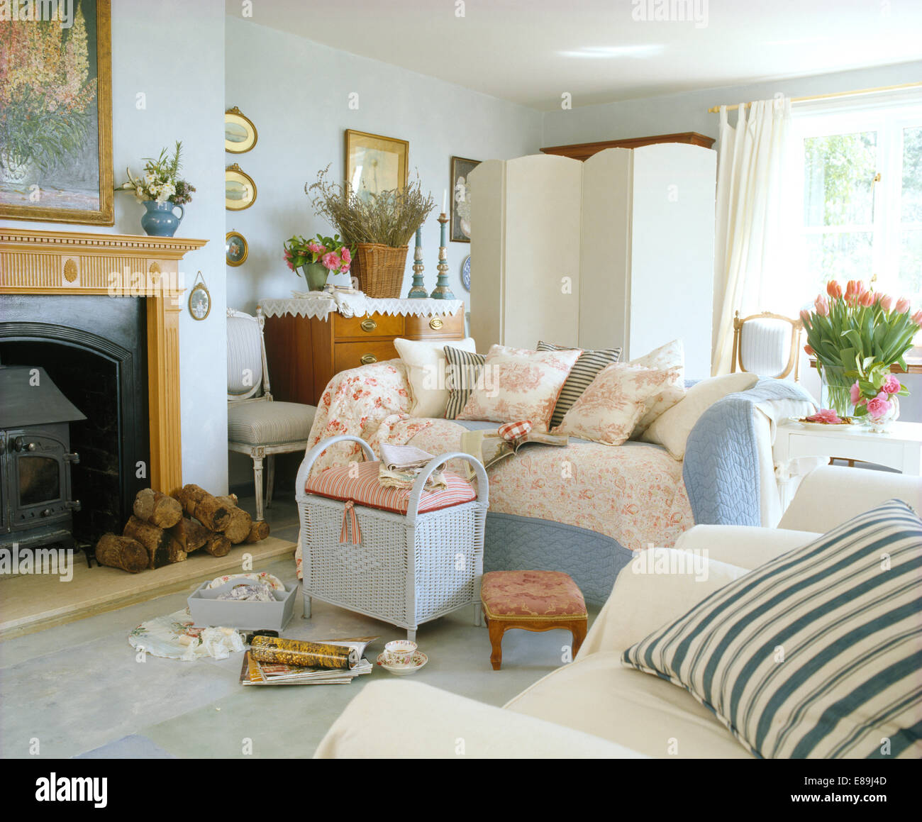 Gesteppte Kissen und wirft auf Sofa mit hölzernen brennenden Kamin Ofen im Wohnzimmer cottage Stockfoto