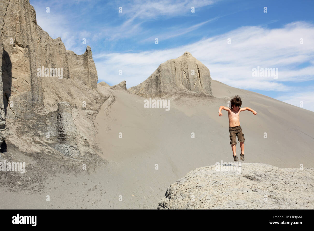 Junge springt auf Sanddünen Stockfoto