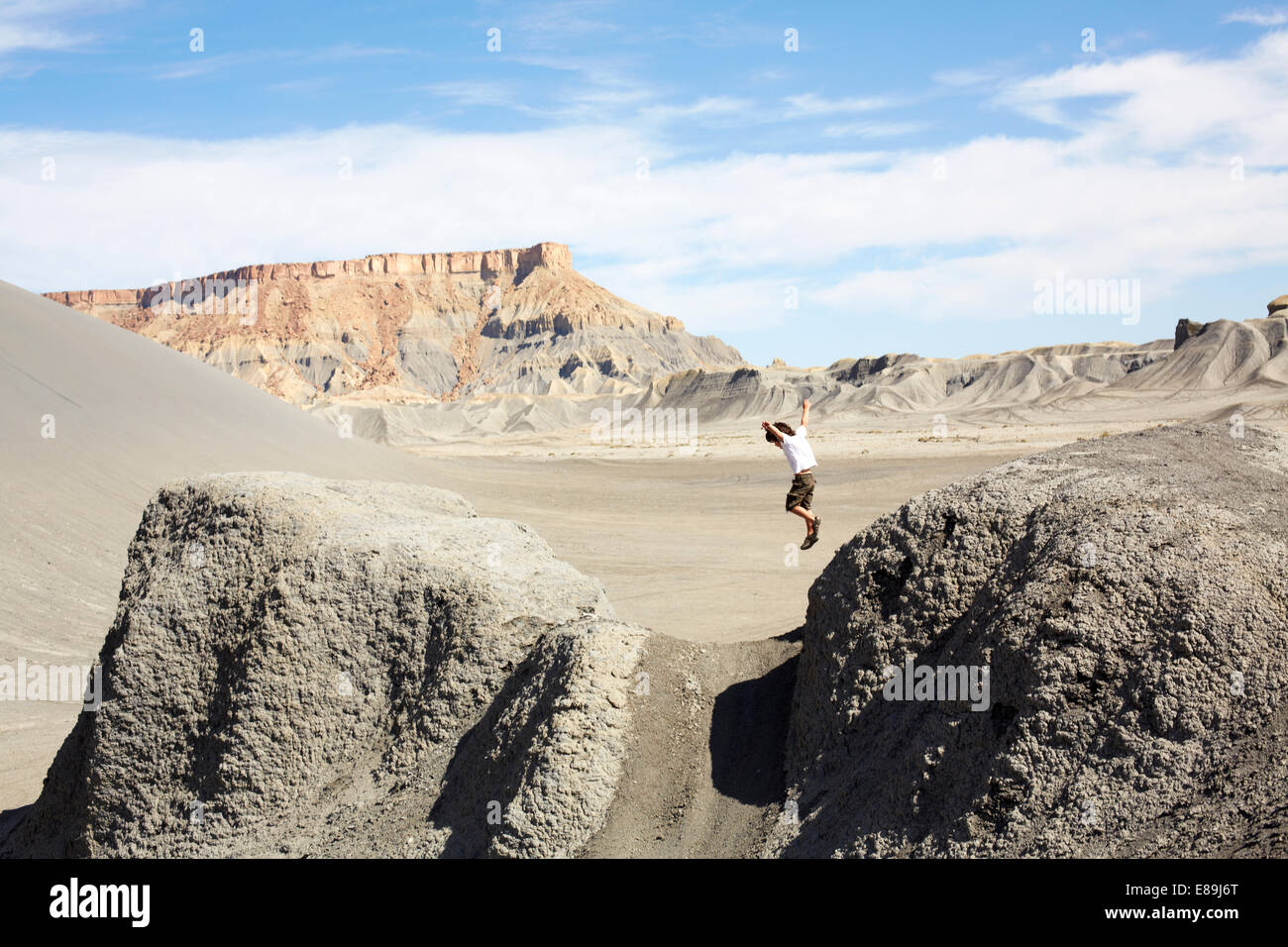 Junge, springen von Felsen in der Wüste Stockfoto