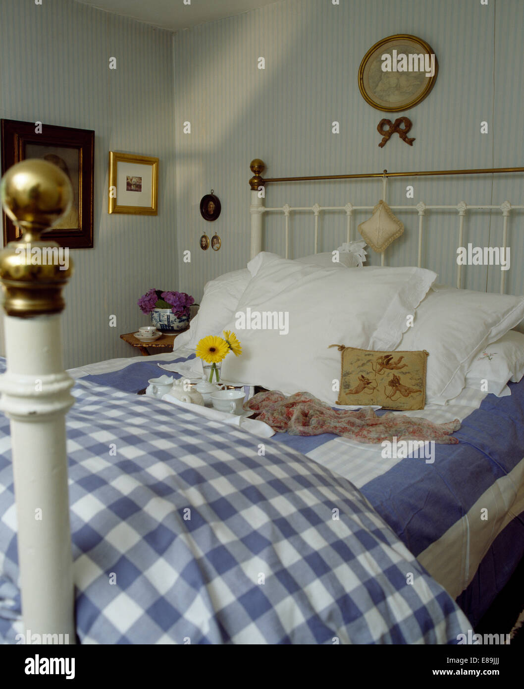 Blau + weiß aufgegebenes Bettdecke auf dem Bett mit breit gestreiften Blatt und weißen Kissen im Land Schlafzimmer Stockfoto