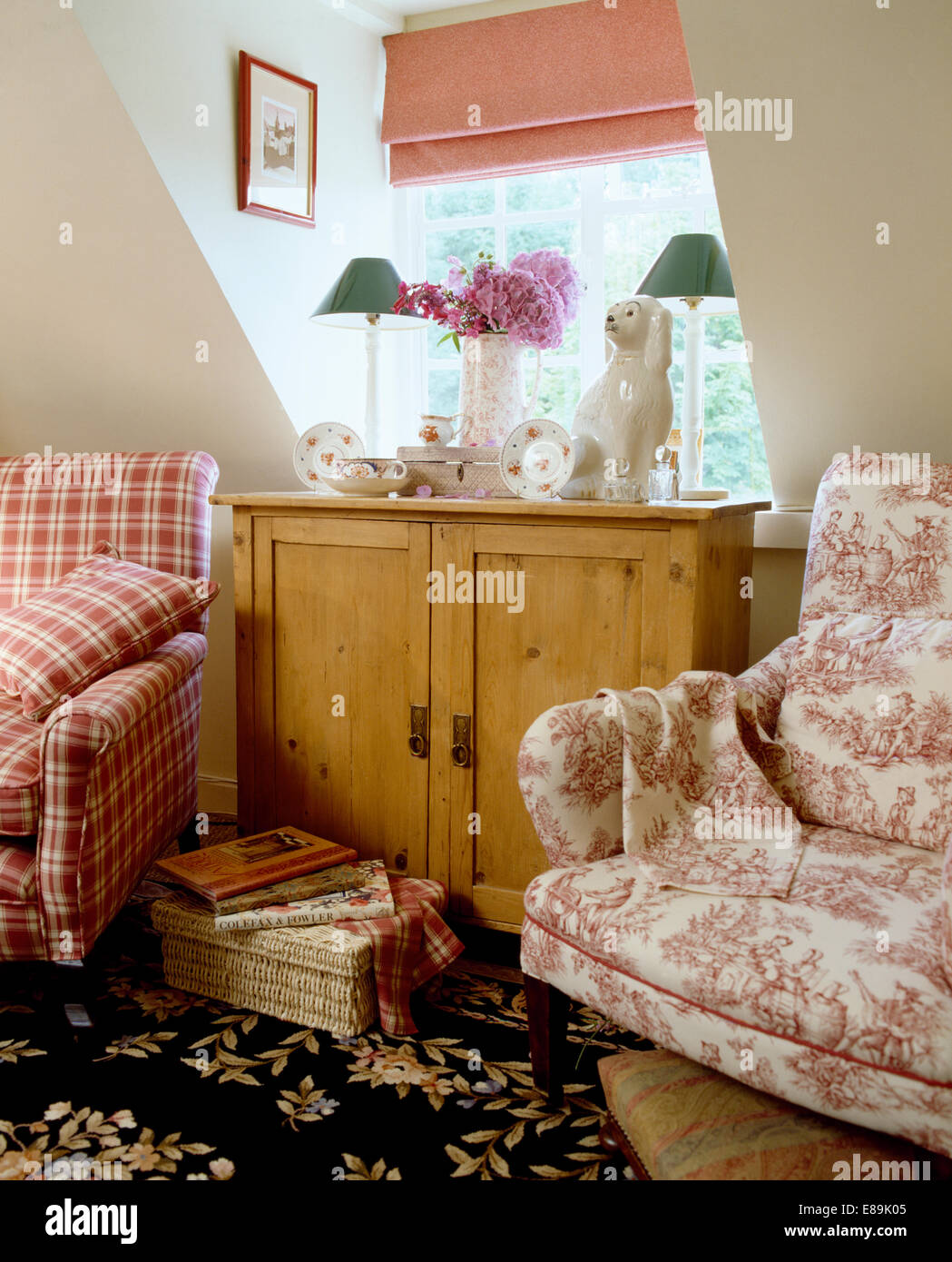 Rosa + weiß Toile-de-Jouy Sessel und aufgegebenen Stuhl auf beiden Seiten auf Kiefer Schrank vor Dachboden Fenster Stockfoto