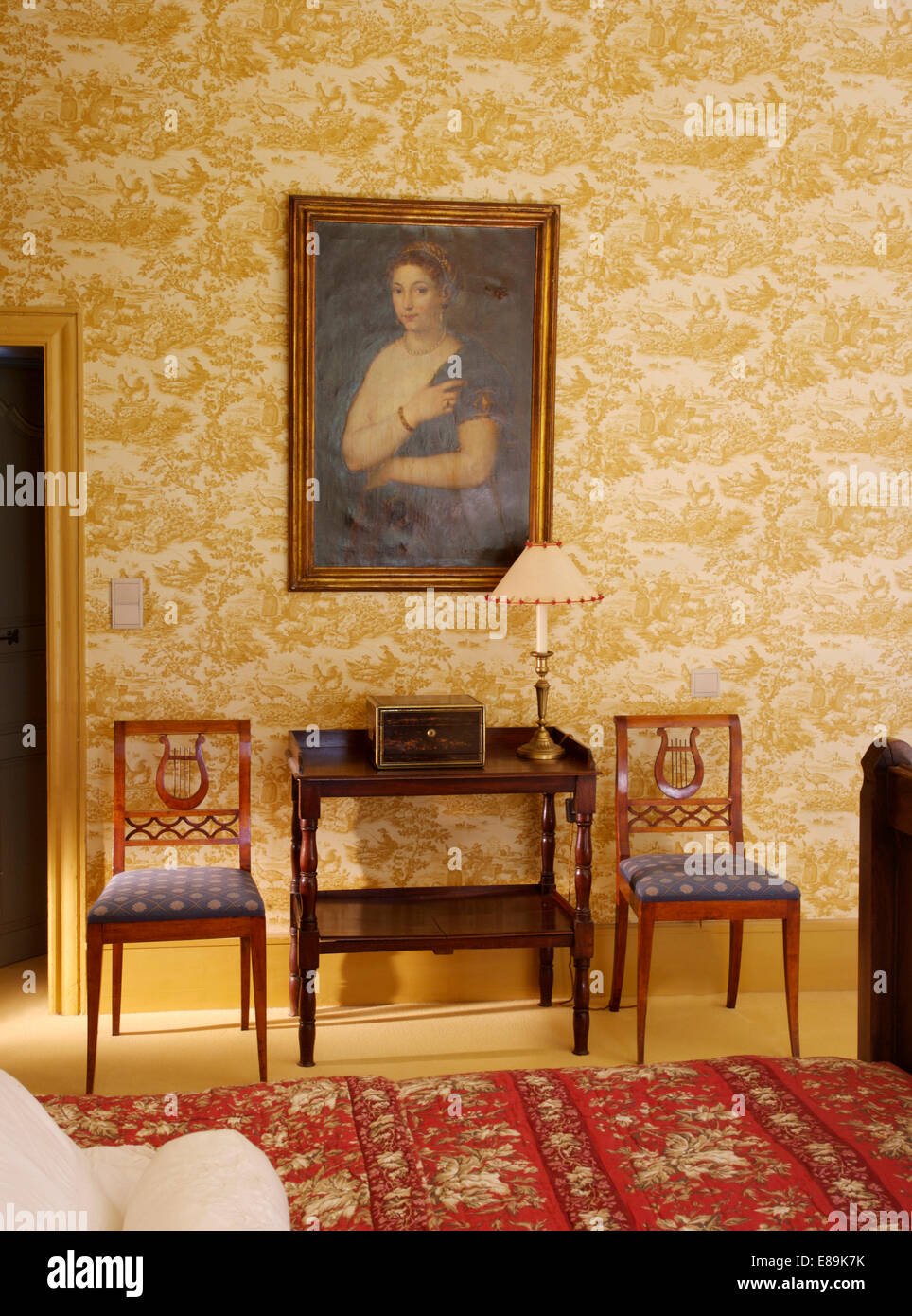 Große Porträt an Wand über antike Konsole Tisch und Stühle im Land Schlafzimmer mit neutralen Toile De Jouy Tapete Stockfoto