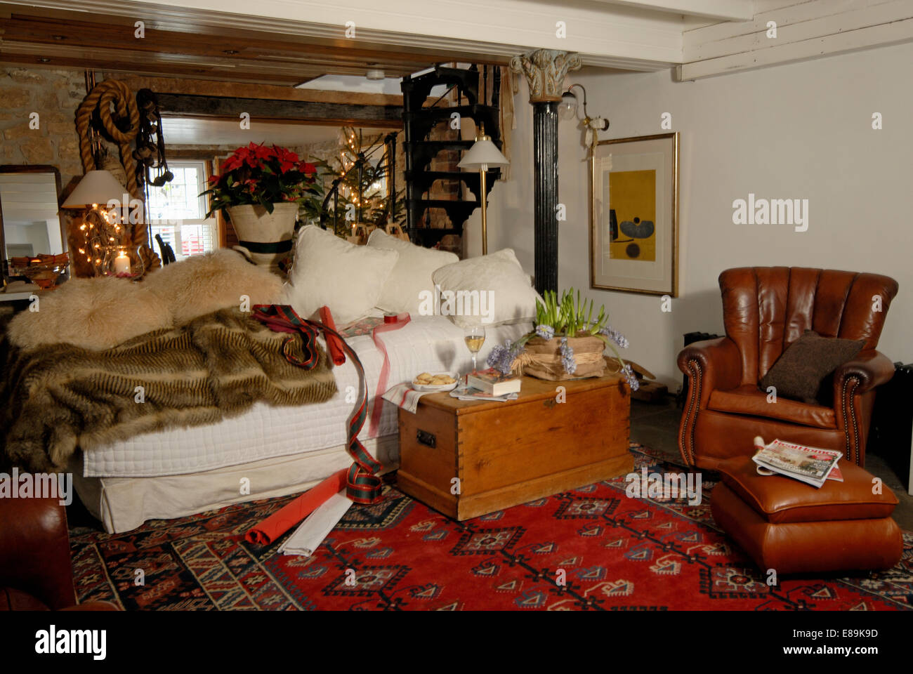 Kunstpelz werfen und cremefarbenen Kissen auf Sofa im Wohnzimmer Cottage mit Holzkiste und Ledersessel Stockfoto