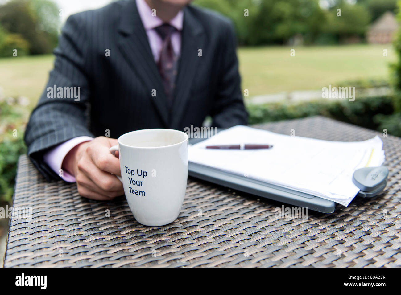 ein Business-Mann sitzt an einem Tisch, trinken Kaffee oder Tee aus einem Becher während der Arbeit Stockfoto