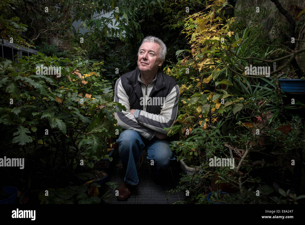 stilisierte Foto eines Mannes hockend in einem Garten umgeben von Pflanzen Stockfoto