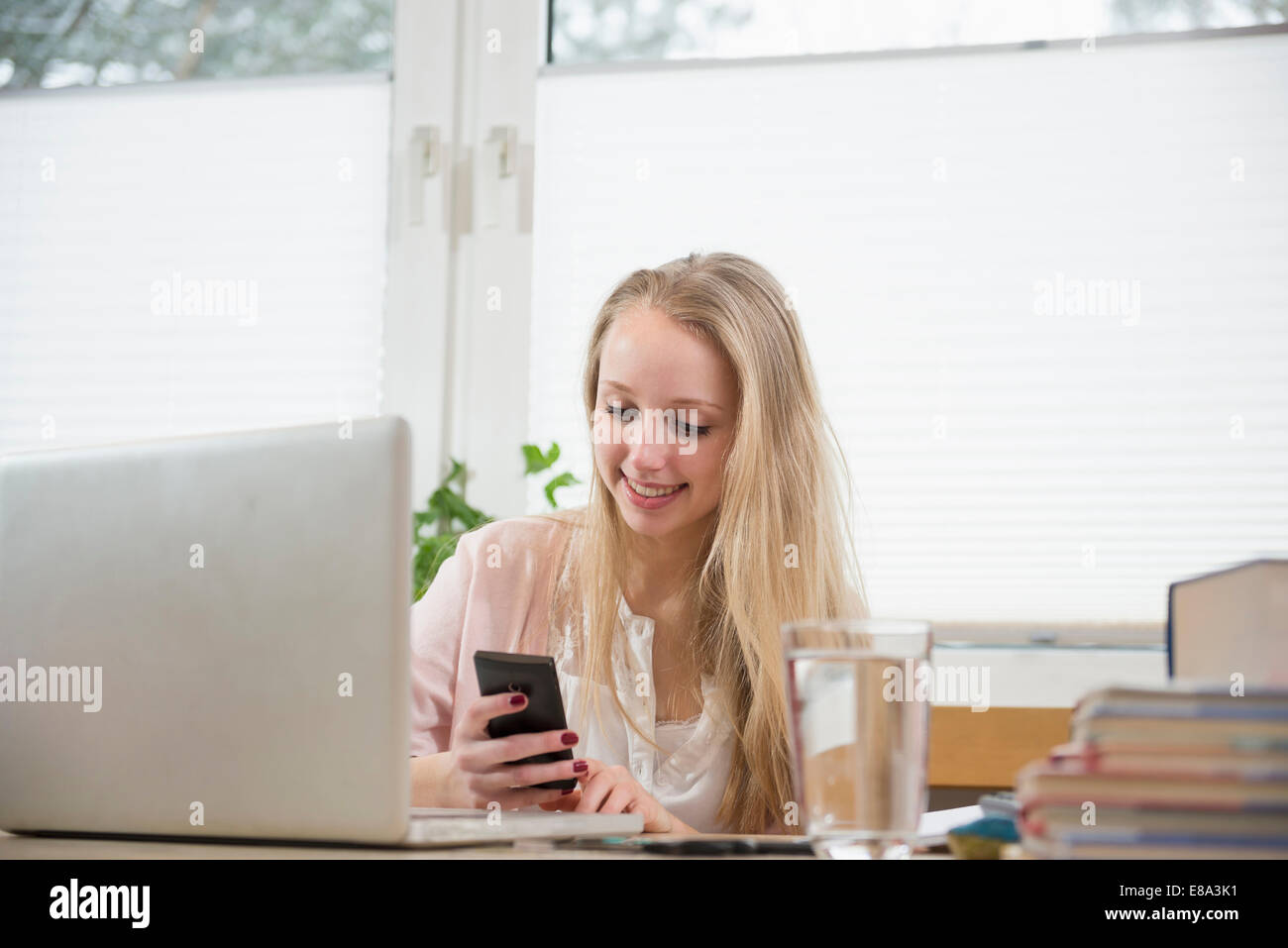 Teenager-Mädchen mit Handy und Laptop, Lächeln Stockfoto