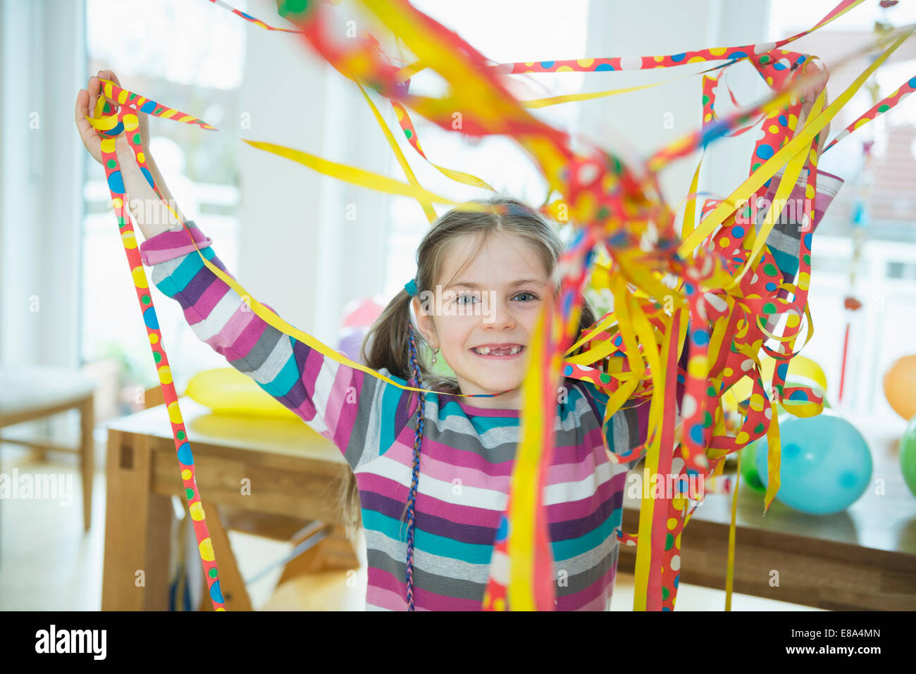 Porträt eines Mädchens mit Blowout Papier Streamer auf Geburtstagsparty, Lächeln Stockfoto