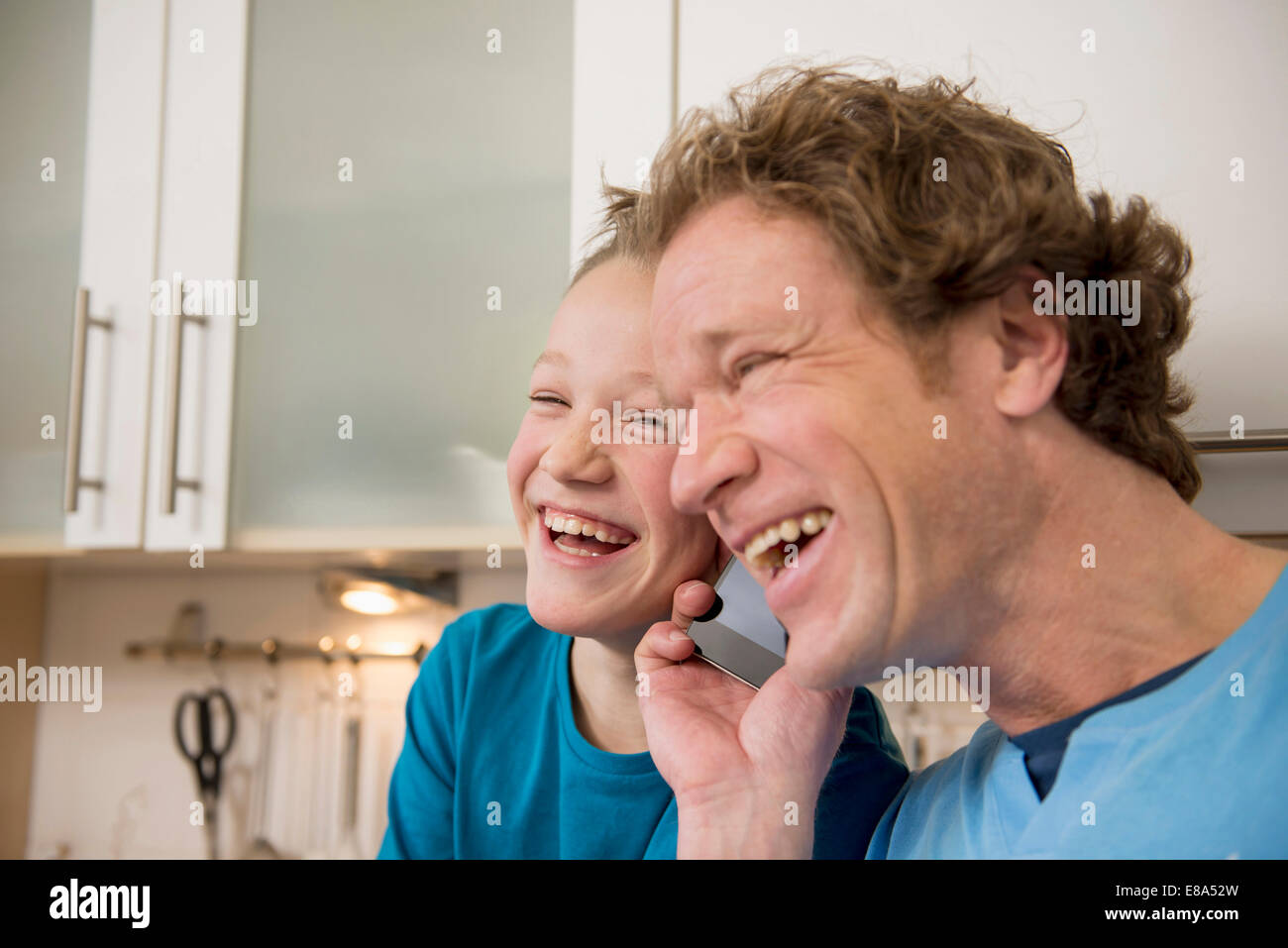 Lachen, Vater und Sohn mit Handy in Küche Stockfoto