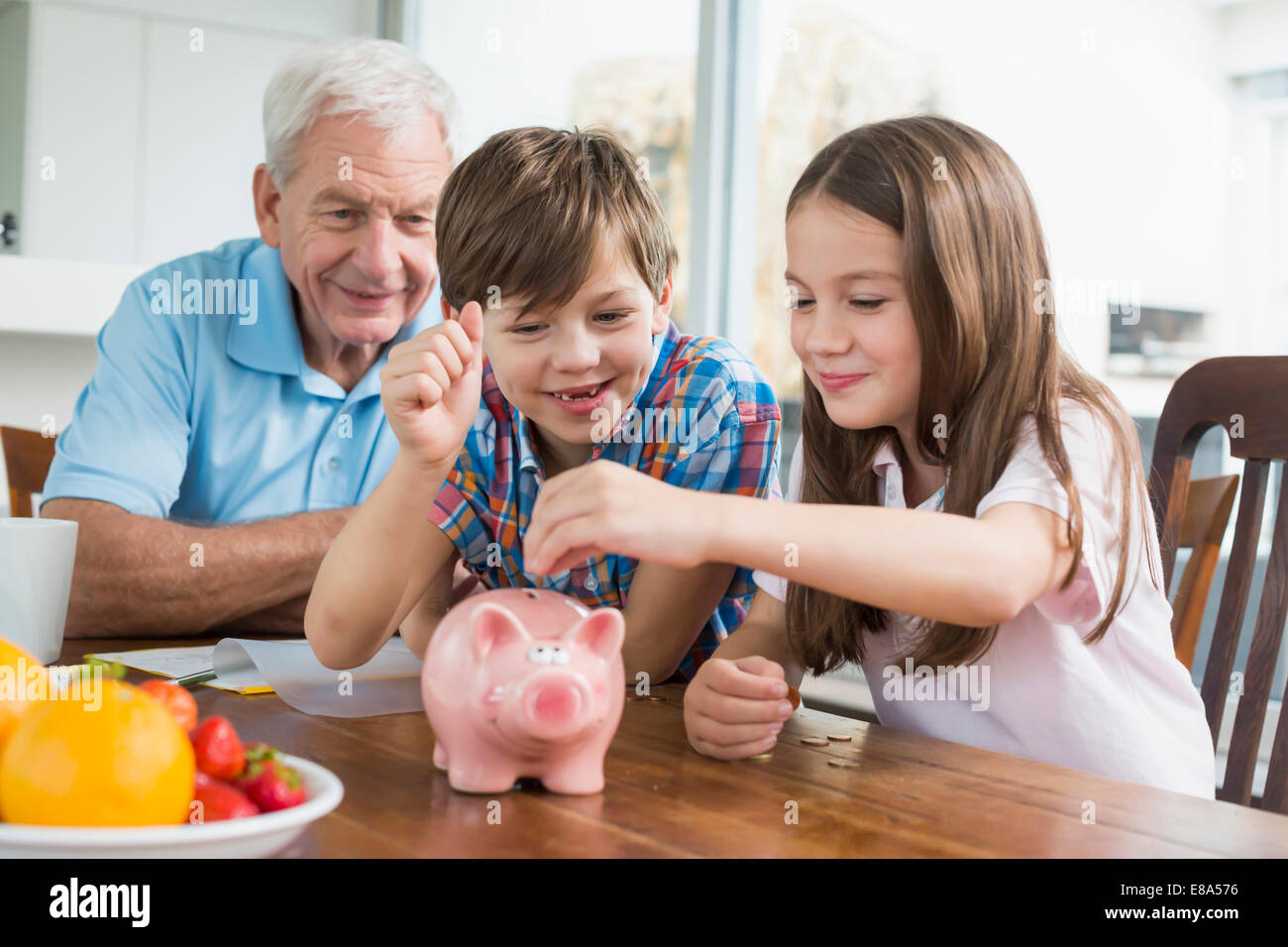 Zwei Kindern und Großvater mit Sparschwein Stockfoto