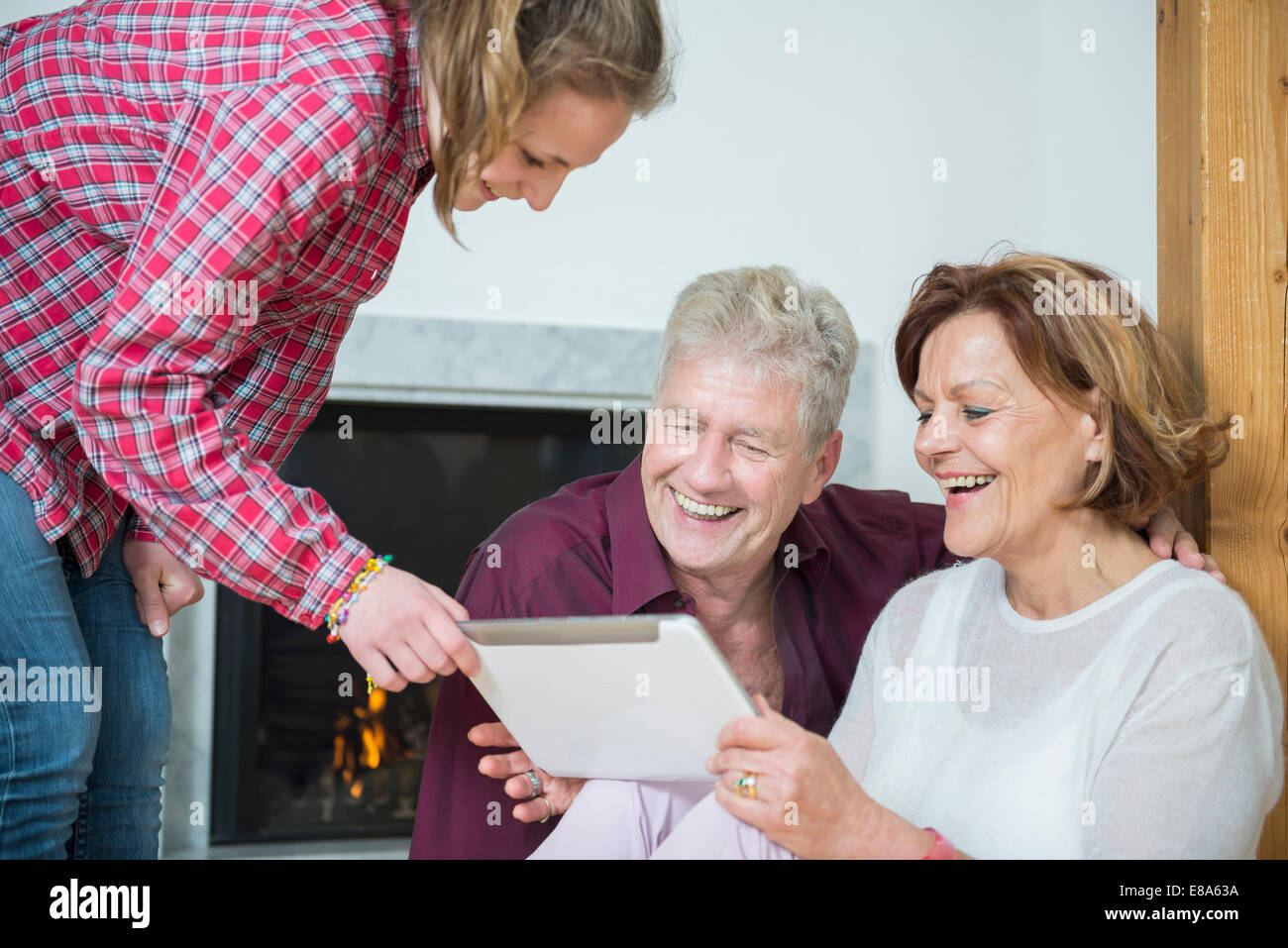 Enkelin zeigen etwas auf digital-Tablette zu ihren Großeltern, Lächeln Stockfoto