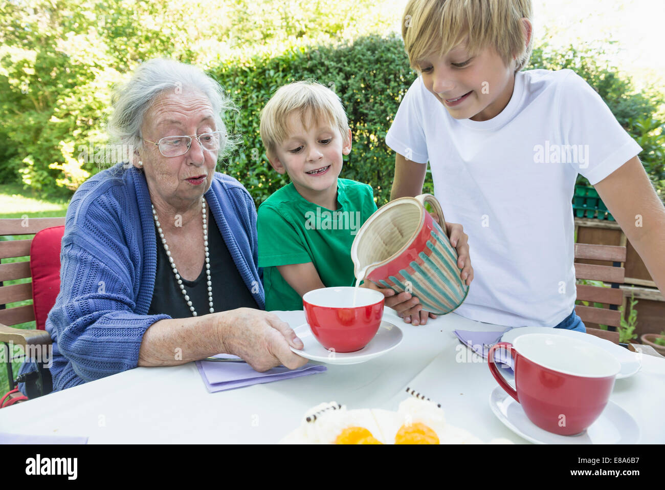 Enkel Gießen Milch in seine Großmütter-Tasse Stockfoto