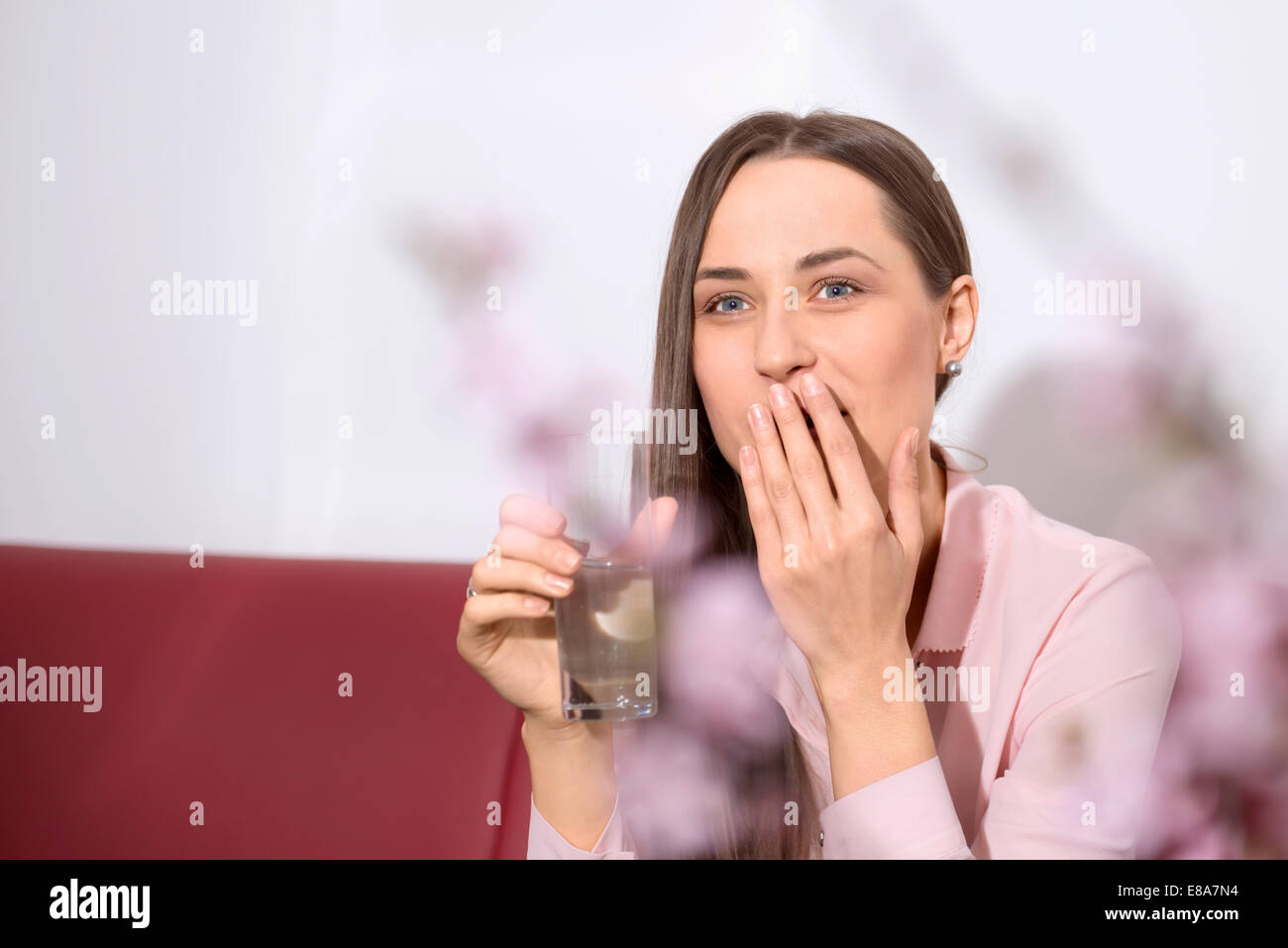 Junge Frau Sofa trinken Wasser Aufstoßen Stockfoto