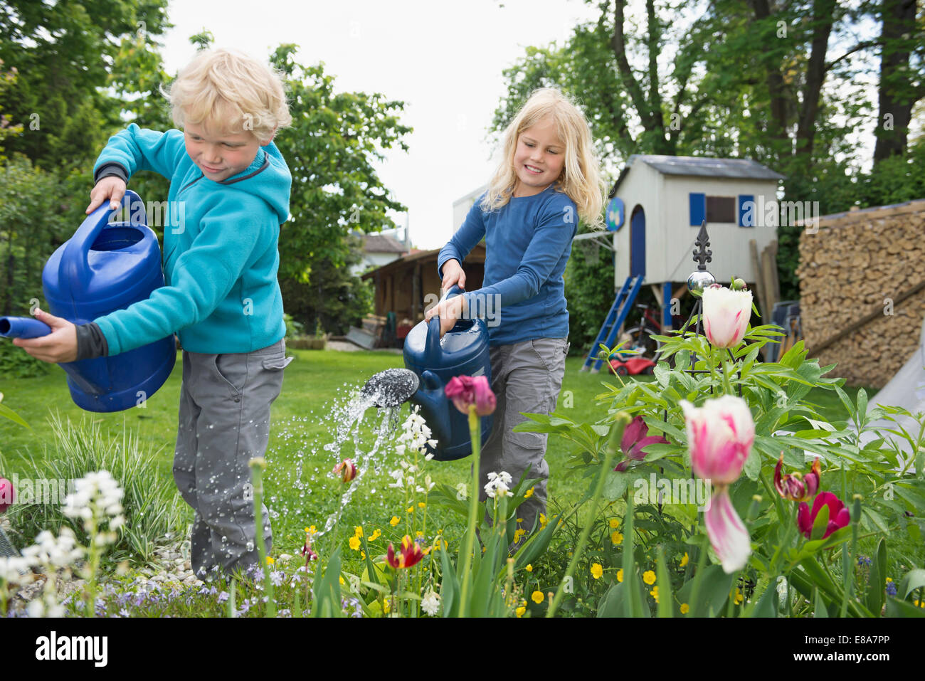 Zwei junge blonde Kinder Blumen im Garten gießen Stockfotografie - Alamy