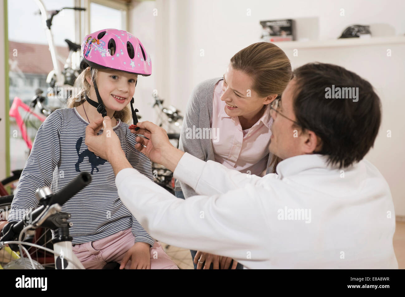 Verkäufer hilft Mädchen Fahrradhelm zu tragen Stockfoto