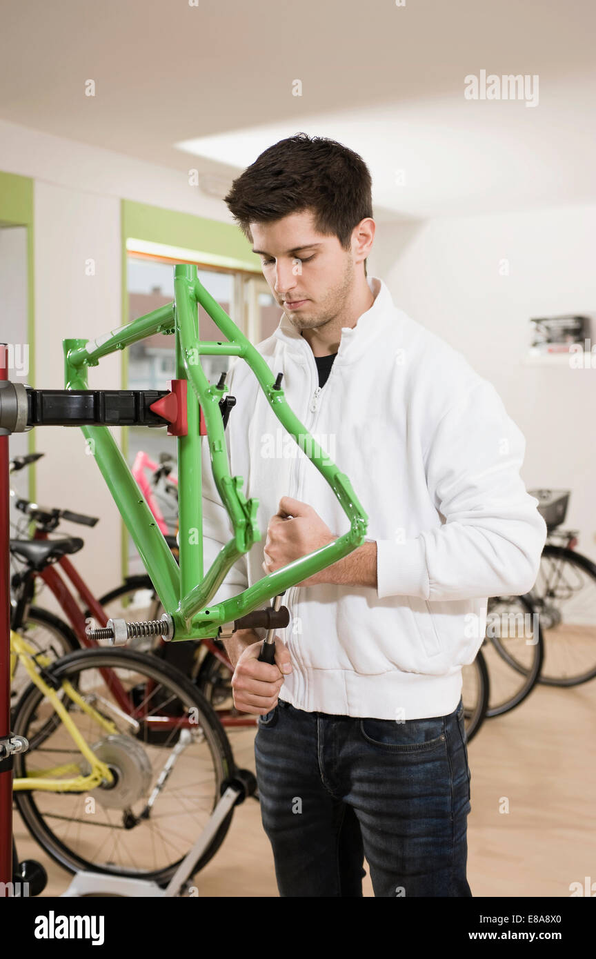 Junger Mann arbeitet an Fahrradrahmen Stockfoto
